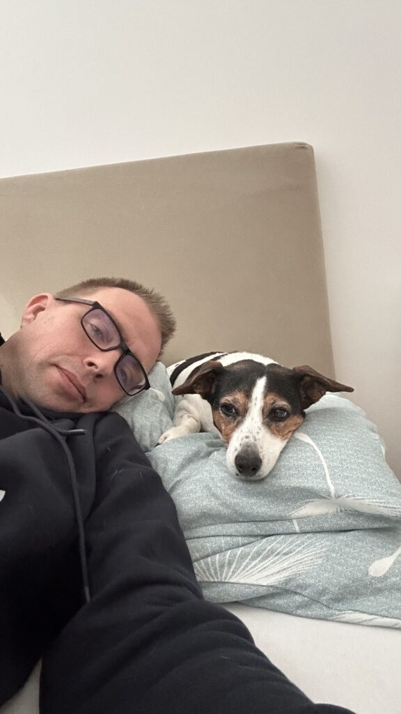 Stepan and his dog Pasha resting on the bed, Pasha with her head on the pillow